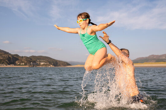 Child girl jumping into sea. Vacation activity.