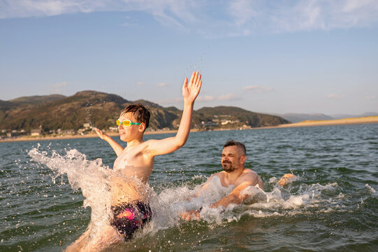 Happy teen boy jumping into sea water.