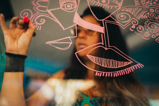 Female artist drawing dribbles on art studio window