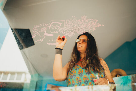 Female artist painting dribbles on art studio window