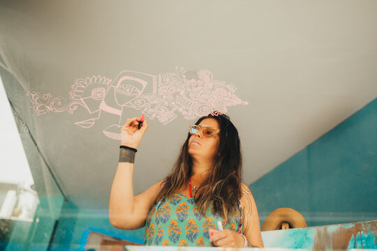 Female artist dribbling on art studio window