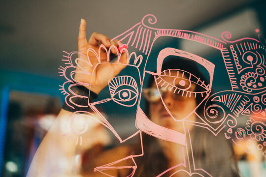 Female artist drawing dribbles on art studio window