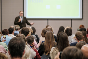 Obraz premium Business presentation in conference room, focused audience listening to speaker, lecture and public meeting atmosphere, professional event and learning environment.