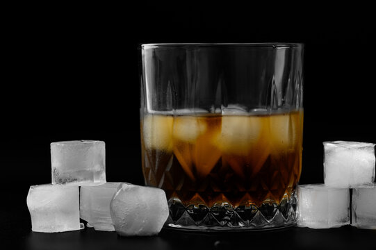Glass of scotch with ice, isolated drink on black background, wallpaper, dark poster