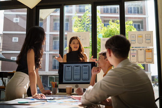 UX UI designers brainstorming and presenting mobile application layouts with wireframes and mockups.