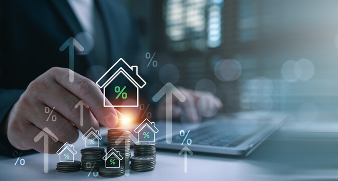 Businessman hand putting coin on stack with virtual house and percentage icon. Conceptual for rising real estate interest rates, mortgage loan calculation, property tax, and financial investment.