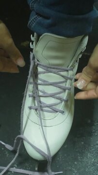 Skater Tightens Laces Before Beginning Movement. Focus On Last Adjustments Prior To Initial Skating Glide. Skater Carefully Secures Laces And Concentrates Before Starting Very First Move