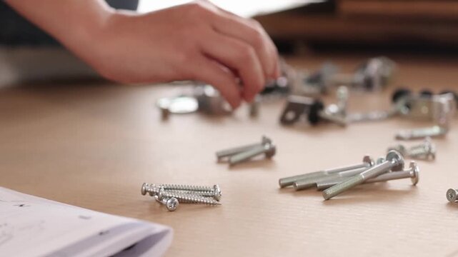 Close Up of Hands Sorting Metal Screws and Bolts on Table
