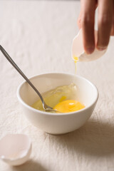 Close-up of woman's hands holding a fresh white organic egg, preparing for cooking in the kitchen
