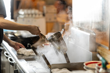 Chef Preparing Ramen in Japanese Noodle Shop with Steam Rising