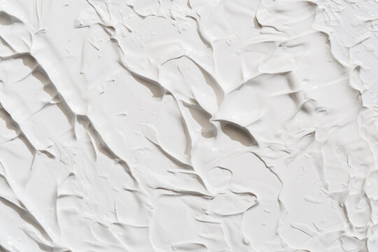 Thick white clay or cream texture with bold spatula ridges and soft shadows, abstract background for luxury skincare branding.