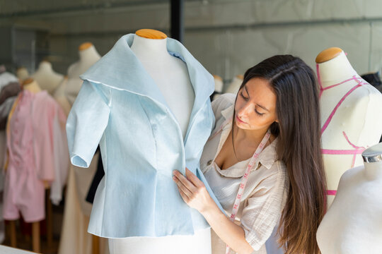 Young fashion designer fitting clothes on dressmaker's model