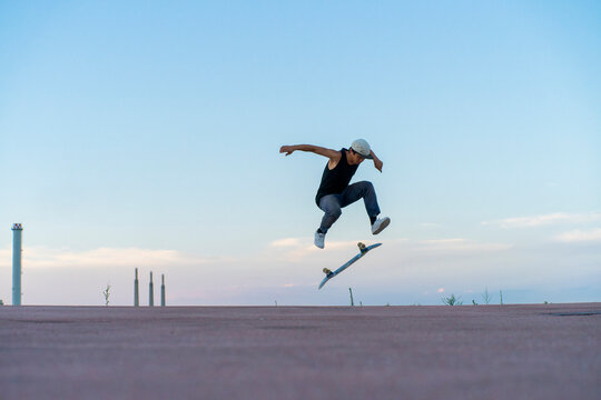 Young man doing a skateboard trick on a lane at dusk