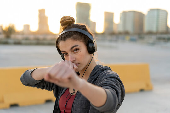 Sportive young woman with headphones during workout, boxing
