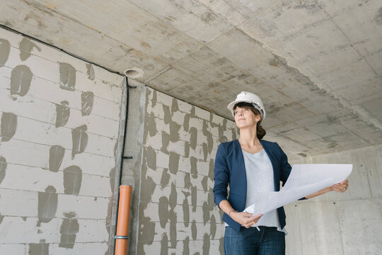 Female architect checking architectural plan on construction site