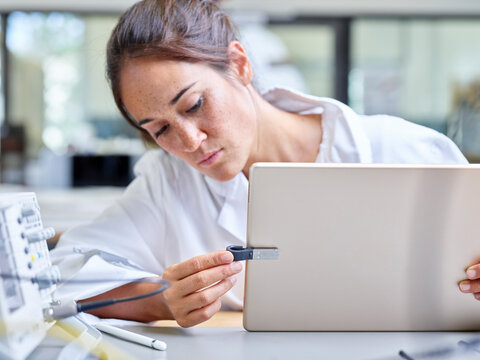 Female technician working in research laboratory, tablet and usb stick
