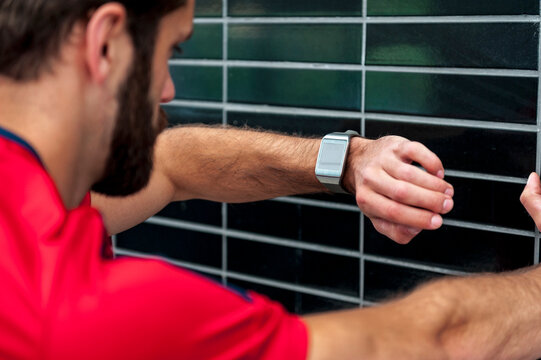 Man having a break from running checking the time on a smartwatch