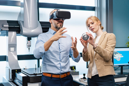 Businessman and businesswoman withVR glasses and workpiece in factory