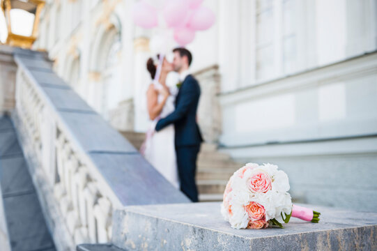Bridal bouquet with kissing bridal couple in the background