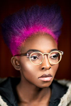 Portrait of young woman with pink and purple dyed hair wearing fashionable glasses
