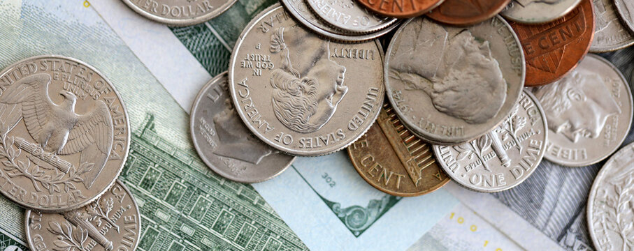 Big amount of United States coins on hundred dollar money bills arranged in chaotic order