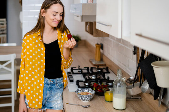 Young woman having breakfast in kitchen at home