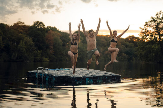 Friends having fun at the lake, jumping from bathing platform