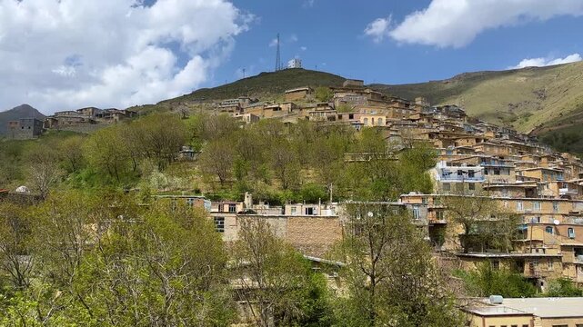travel to Kurdistan rural village terraced with adobe mud brick houses in zagros mountain in iran iraq Kurdish culture traditional architecture hillside blue sky countryside agriculture walnut garden