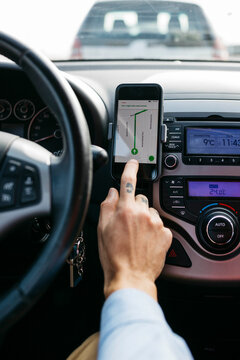 Close-up of man with tattooed hand driving car using cell phone as navigation system