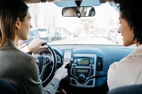 Two women driving in a car through the city using a telephone navigation app
