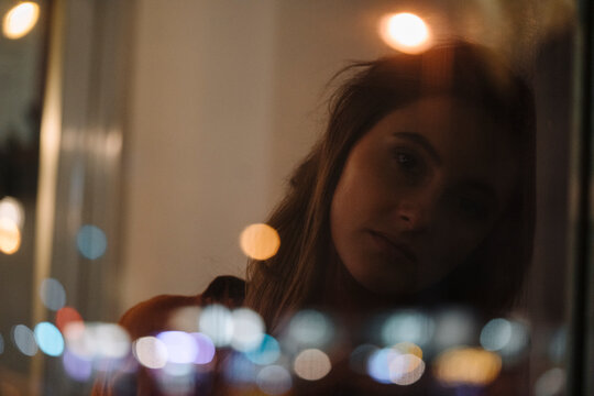 Portrait of serious young woman behind windowpane