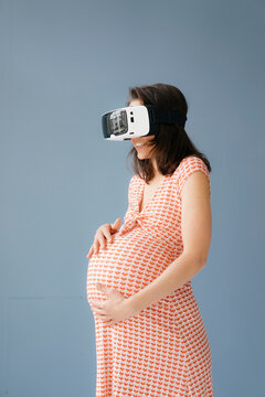 Woman pretending to be pregnant, using VR glasses