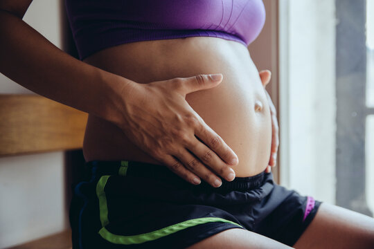 Sporty pregnant woman holding her belly
