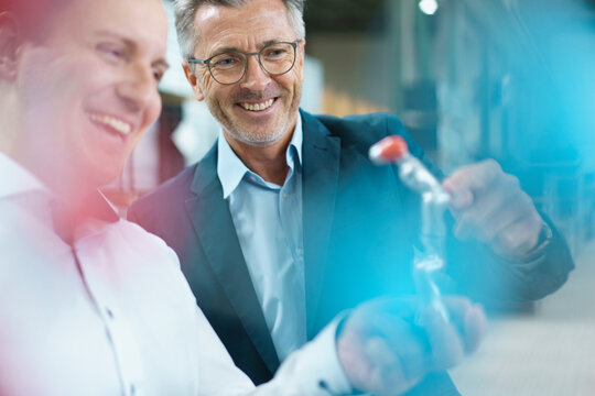 Two happy businessmen holding product in a factory