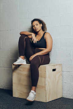 Portrait of confident athletic young woman sitting on a box