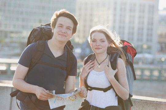 Germany, Berlin, Young couple traveling Berlin with backpacks, looking at map