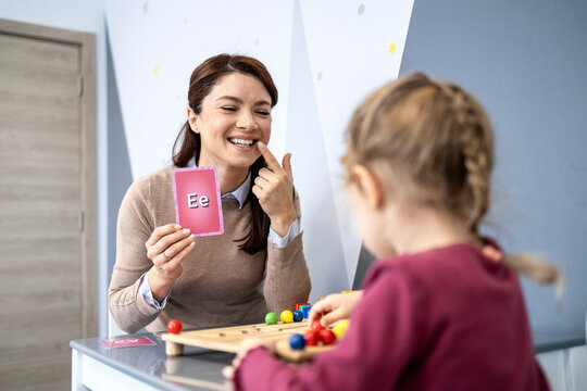 Speech therapist teaching child articulation using flashcard with letter e, demonstrating clear pronunciation during a developmental language lesson