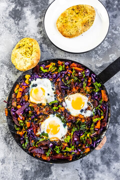 Pan of beetroot shakshouka with chard, carrots, tomatoes, red cabbage and pita bread
