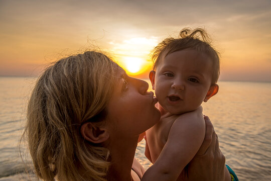Vietnam, Phu Quoc island, Ong Lang beach, Mother kissing baby in beach at sunset
