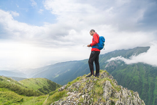 Man standing on top of a hill and checking his map in the Carpathian Mountains, Romania