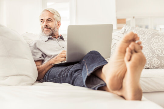 Mature man using laptop on couch at home