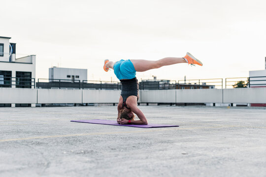 Woman doing a headstand on parking level in the city