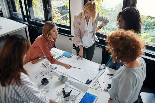 Businesswomen having a meeting in office with blueprints on table