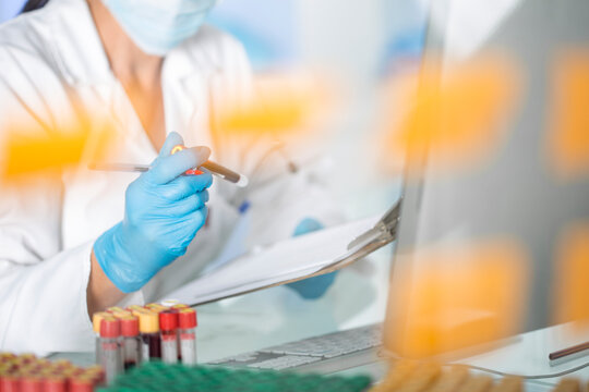 Close-up of lab technician examining test tubes with liquid in laboratory