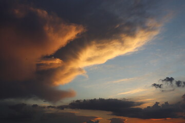 Fototapeta premium Dark dramatic storm clouds mixed with warm sunset light