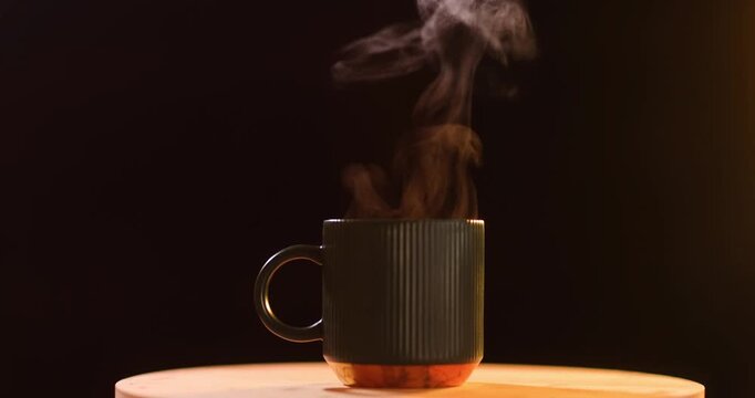 Black mug with steam on table in studio, hot drink with cozy steam, morning relaxation, warmth, coffee break, studio, calm, beverage, black, steam, hot, morning, mug, coffee
