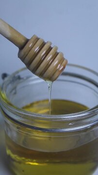 honey dripping from a jar on white background. Vertical video