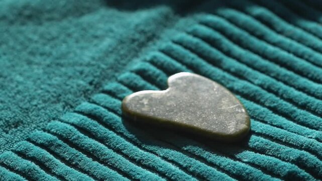 Guasha scraper lies on a towel. Guasha scraper made of natural serpentinite stone tool with soft towel, close-up