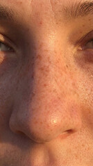 Naklejka premium Young person looks at camera with freckles on face. Soft light reflects on smooth skin. Setting suggests outdoor activity during sunset. Concept of beauty, youth, wellness