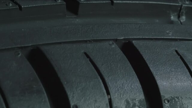 Contrasting Wheel Tread Pattern. Car wheel slowly rotates in front of the camera close-up on a black background